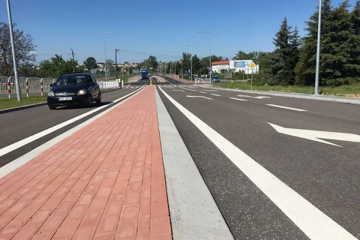 Nowy chodnik i droga rowerowa w mieście na trasie Gostyń-Kórnik. Czarny samochód jedzie po jezdni.